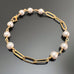 6mm white crystal pearls linked in groups of three interspersed within a gold tone paperclip style chain.
