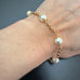 8mm white crystal pearls are stationed evenly throughout a gold tone heavy rolo style chain. shown as worn