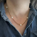 8mm white crystal pearls are stationed evenly throughout a gold tone heavy rolo style chain. shown as worn.