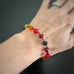 yellow, orange and red spectrum faceted glass beaded bracelet ,with hand wrapped, secure links, displayed on a table. Shown worn on wrist.