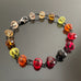 yellow, orange and red spectrum faceted glass beaded bracelet ,with hand wrapped, secure links, displayed on a table.