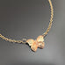 dainty gold antiqued brass butterfly necklace on a dark gray background