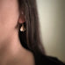Small oxidized brass ginkgo leaf earrings shown on model.