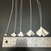 Sterling silver ginkgo leaf pendant necklaces in five sizes next to ruler.