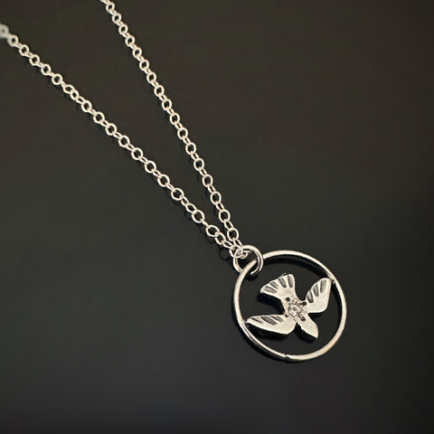 sterling silver dove encircled on a free floating pendant with a small white topaz at the center