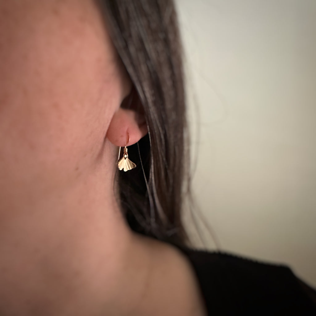 Tiny 14k gold filled ginkgo leaf earrings shown on model.