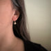 Tiny oxidized brass ginkgo leaf earrings shown on model.