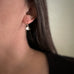 Tiny sterling silver ginkgo leaf earrings on model.