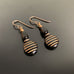 dangle earrings with a black and gold striped coin shaped bead