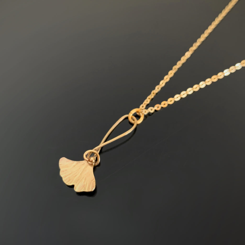 golden ginkgo leaf with a swirling tendril on an shiny delicate necklace chain