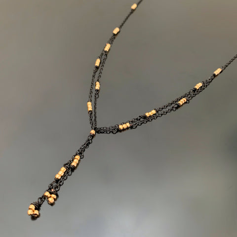 Y shaped necklace made with black chain and gold beads