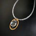 necklace with clear glass teardrop inside a brass oval
