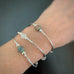 your choice of three silver tube stretch bangle bracelets with anciend looking glass in green white and purple