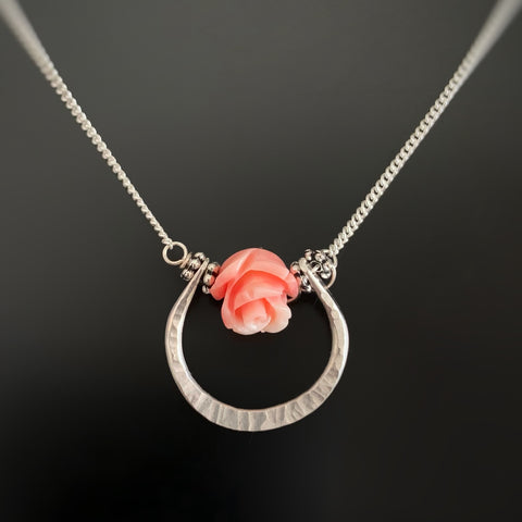 Handmade sterling silver horseshoe shaped pendant with carved rose bead in a peachy pink coral color.
