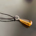 amber teardrop pendant on black cord with a twisted silver circle