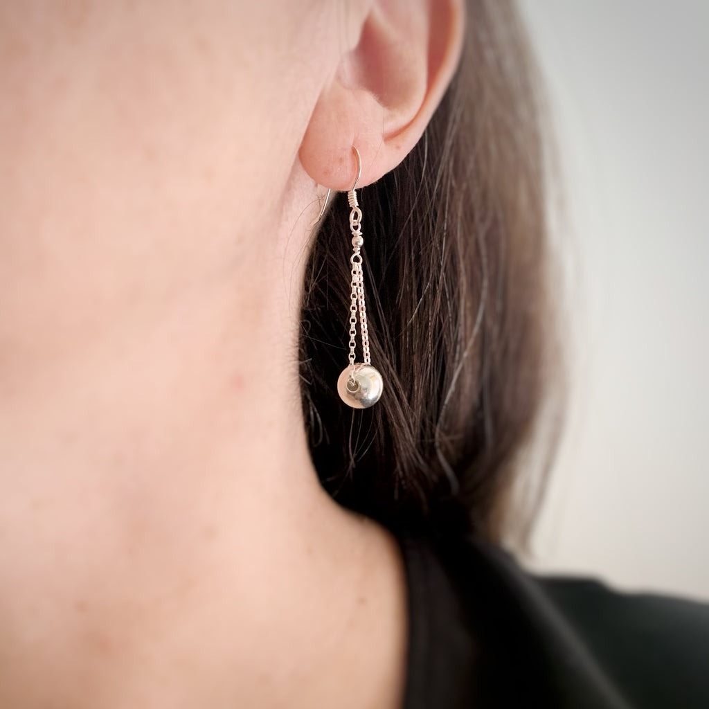 Sterling silver ball drop earrings with chain shown on model.