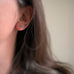 Tiny round turquoise stud earring in sterling silver shown on model.