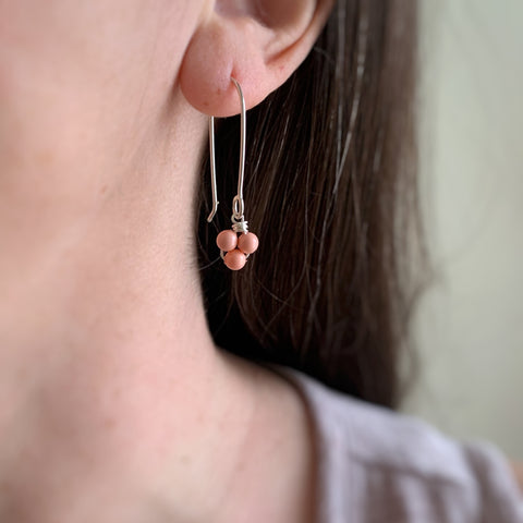 Sterling silver drop earrings with small pink coral colored beads in a triplet formation.